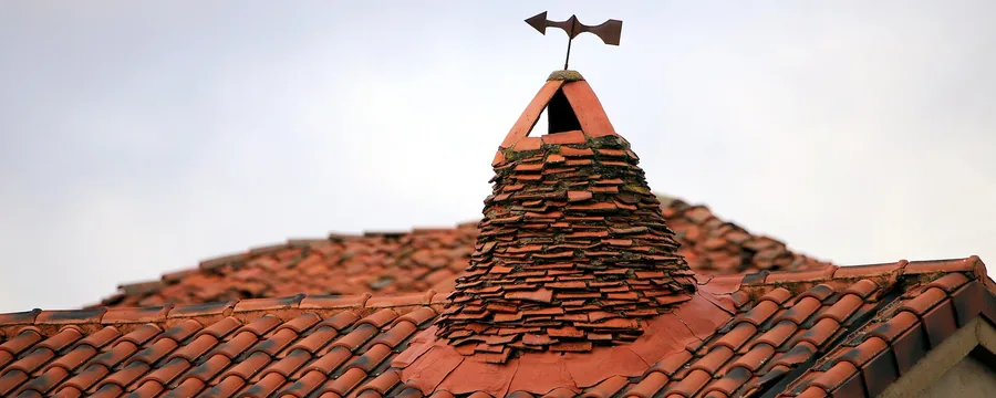 Una chimenea pinariega: cono de tejas rematado por una veleta