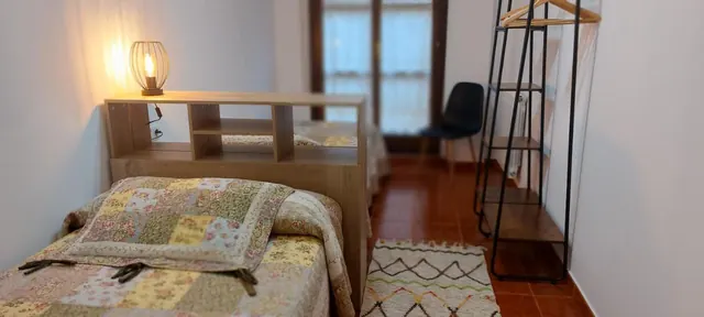 Dormitorio con cabecero-estantería y alfombra